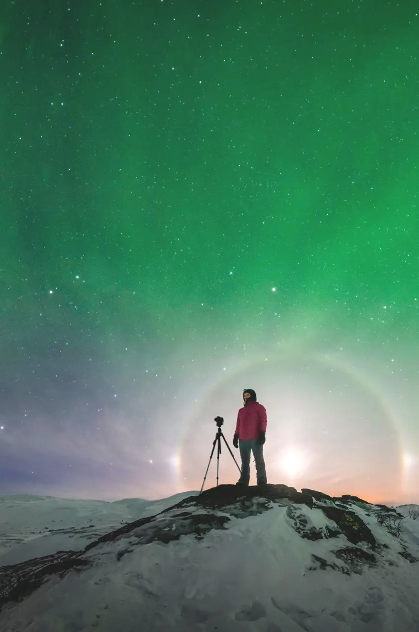 a person stands with his camera at the top of the mountain in the northern lights. photo: Göran Strand/imagebank.sweden.se
