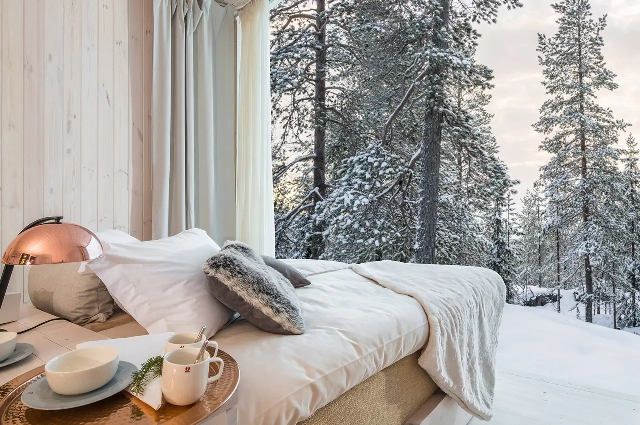 arctic tree house seen from inside a room with view over the snowy trees