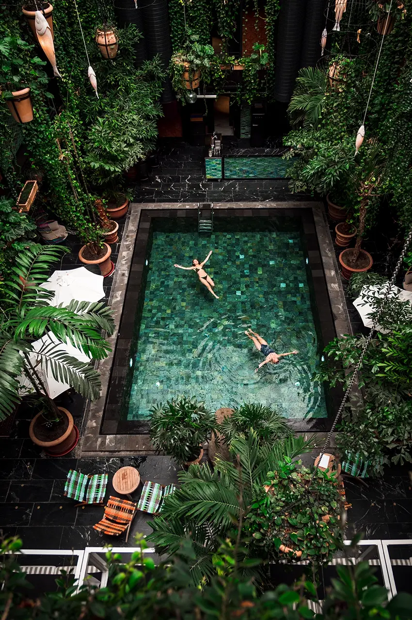 pool couple laying in the pool surrounded by big plants at the Guldsmeden Hotel